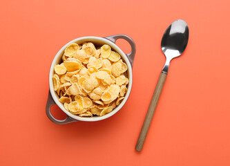 Pot with tasty cornflakes and spoon on color background