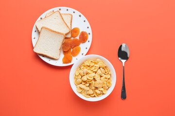 Bowl with tasty cornflakes, bread and dried apricots on color background