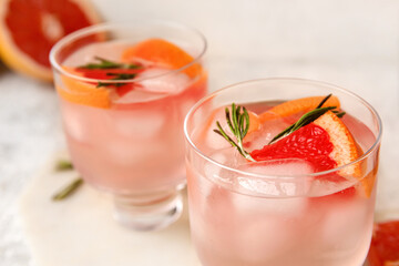 Glasses of tasty grapefruit margarita on light background
