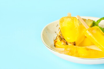 Plate with tasty pineapple popsicles on color background