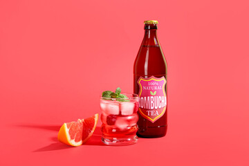 Bottle and glass of tasty kombucha tea on color background