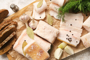 Wooden board with salted lard and bread on light background
