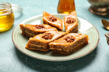 Plate with tasty baklava on blue background