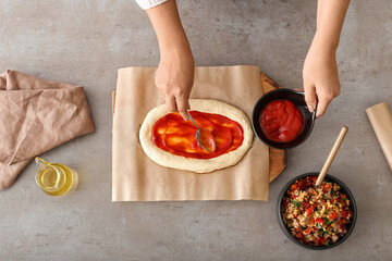 Woman preparing Turkish Pizza on grey background