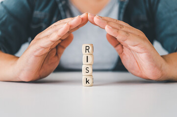 Hand protect wooden block with the word "RISK". Concept prevent risk.