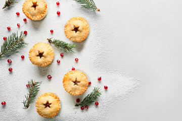 Composition with tasty Christmas mince pies, cranberry and fir branches on light background