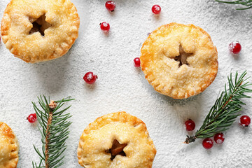 Tasty mince pies, cranberry and fir branches on light background