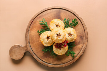 Board with Christmas mince pies, cranberry and fir branches on color background © Pixel-Shot