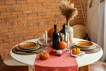 Dining table with pumpkins near brick wall