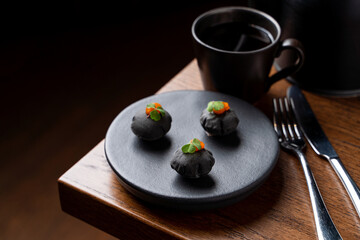 Obraz na płótnie Canvas Black puffs with red caviar as a gourmet elegant appetizer for a good wine