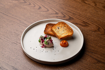 A small portion of foie gras on a wide big dish in a restaurant, top view, menu photography