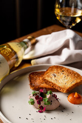 Photo for an expensive french restaurant menu: a small portion of foie gras, served with crispy bread and a glass of white wine © Tkachenko Alexey