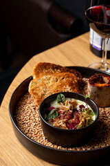Close up of fine dining beef tartare with a baked bone, crispy rye toasts and a glass of red wine, beautiful commercial photo