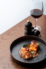 Studio shot of gourmet salmon steaks with sour-sweet sauce and a glass of red wine, side view