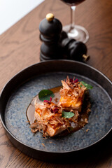 Gourmet salmon steaks with sour-sweet sauce and a bottle of red wine, side view, dark atmospheric restaurant