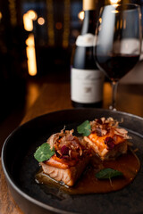 Salmon and wine, a classic fish restaurant set on blurred lights background, side view, close up