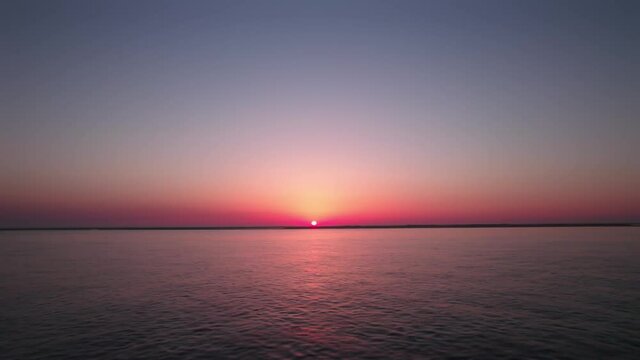 Amazing sunset in the ocean, horizon with beautiful colors, pink and red.
