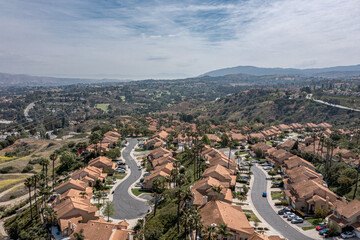 Aerial view of a suburban southern California community in the hills.  Sunny day with silky clouds