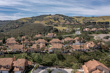 Fototapeta na wymiar Aerial view of a modern southern California neighborhood on a hill with silky clouds.