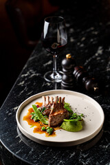 Side view of grilled ribs with red wine in a dark atmosphere of an empty restaurant