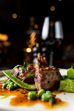 Close mouth watering shot of juicy grilled ribs with red wine and peas puree on a black marble table