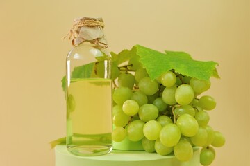 Grape seed oil.bottle and bunch of green grapes on green podium on a beige background. Organic Bio Grape Seed Oil. 