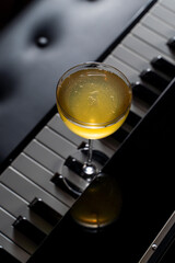 Small yellow aperitif cocktail on a keys of piano, elegant shot in a dark atmosphere