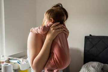 Bedwetting child pee stain on the side of the clothes of baby mother hold her infant child with wet...