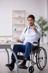 Young male doctor in wheel-chair working in the clinic