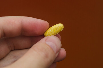 yellow pill in hand. Sports food supplements.