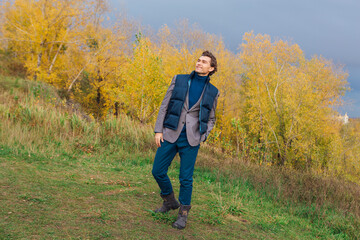 Naklejka na ściany i meble Tall handsome man outdoor in autumn forest on the hill
