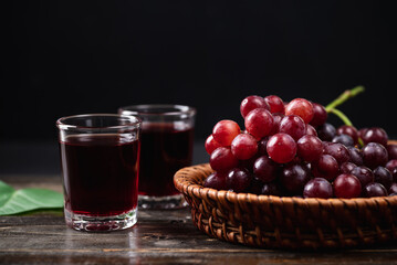 Red grape juice in a glass with fresh grape in a basket on wooden background, Healthy drink, Still...