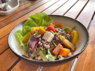 Quinoa salad in ceramic bowl on wooden table, selective focus. Quinoa seeds are rich in protein, dietary fiber, B vitamins, and dietary minerals, good source of antioxidants.