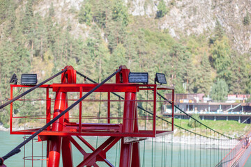 Fototapeta na wymiar A suspension bridge over a wide river in the mountains. Safe crossing of the bridge from one bank to the other.