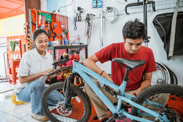 young mechanic assembling a new bicycle using a wrench in the shop