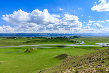 Obraz premium Bayinbuluke grassland natural scenery in Xinjiang,China.The winding river is on the green grassland.
