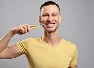 Portrait of happy friendly smiling adult man in yellow t-shirt with toothbrush demonstrates his healthy white teeth after brushing. Healthy vigorous lifestyle concept