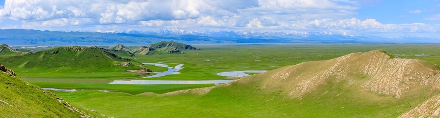 Fototapeta na wymiar Bayinbuluke grassland natural scenery in Xinjiang,China.The winding river is on the green grassland.Panoramic view.