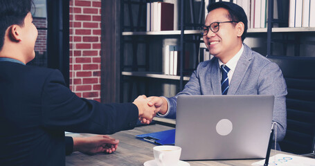 Success collaboration partners sign contract and shake hands after success business joint venture deal. Diversity Businessman shake hands together in a meeting. Trustworthy meeting business concept.