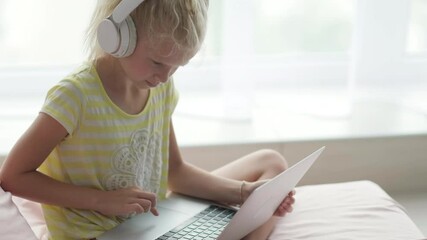 Blonde schoolgirl studying on bed at home doing school homework with laptop. Distance learning online education. Back to school. - Powered by Adobe