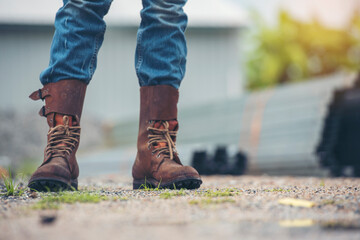 Men wear construction Boots safety footwear for worker at construction site. Engineer Wear Jeans Brown Boots Worker on Background of Refinery. Engineer safety industry fashion footwear walking outdoor