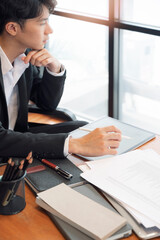 Young asian businessman thinking and worrying about business planning while working in office.