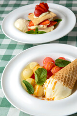 Vanilla ice cream in a cone served with melon and watermelon ice cream scoops in a white plate.