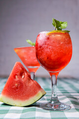 Water melon cocktail and fresh melon, on a table with green plaid tablecloth. Summer drink, cold beverage