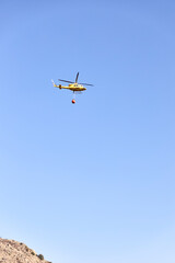 Fototapeta na wymiar Firefighting helicopter transporting water to extinguish a fire. Hazard concept