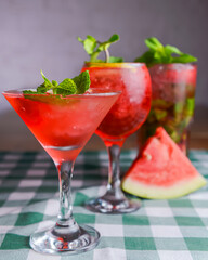 Water melon cocktails and fresh melon, on a table with green plaid tablecloth. Summer drink, cold beverage