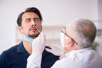 Young male patient visiting old male doctor during pandemic