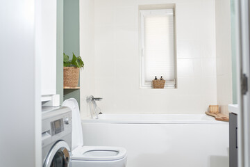 Beautiful bathroom in a new luxury house. The room has an elegant bathroom, a washing machine and a window. High quality photo