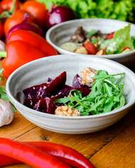 Salad with grated beets and herbs in a bowl on the rustic wooden background with a lot of fresh greenery.