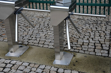 stainless steel entrance turnstiles for tickets. placed outside on cobblestone pavement. it is an...